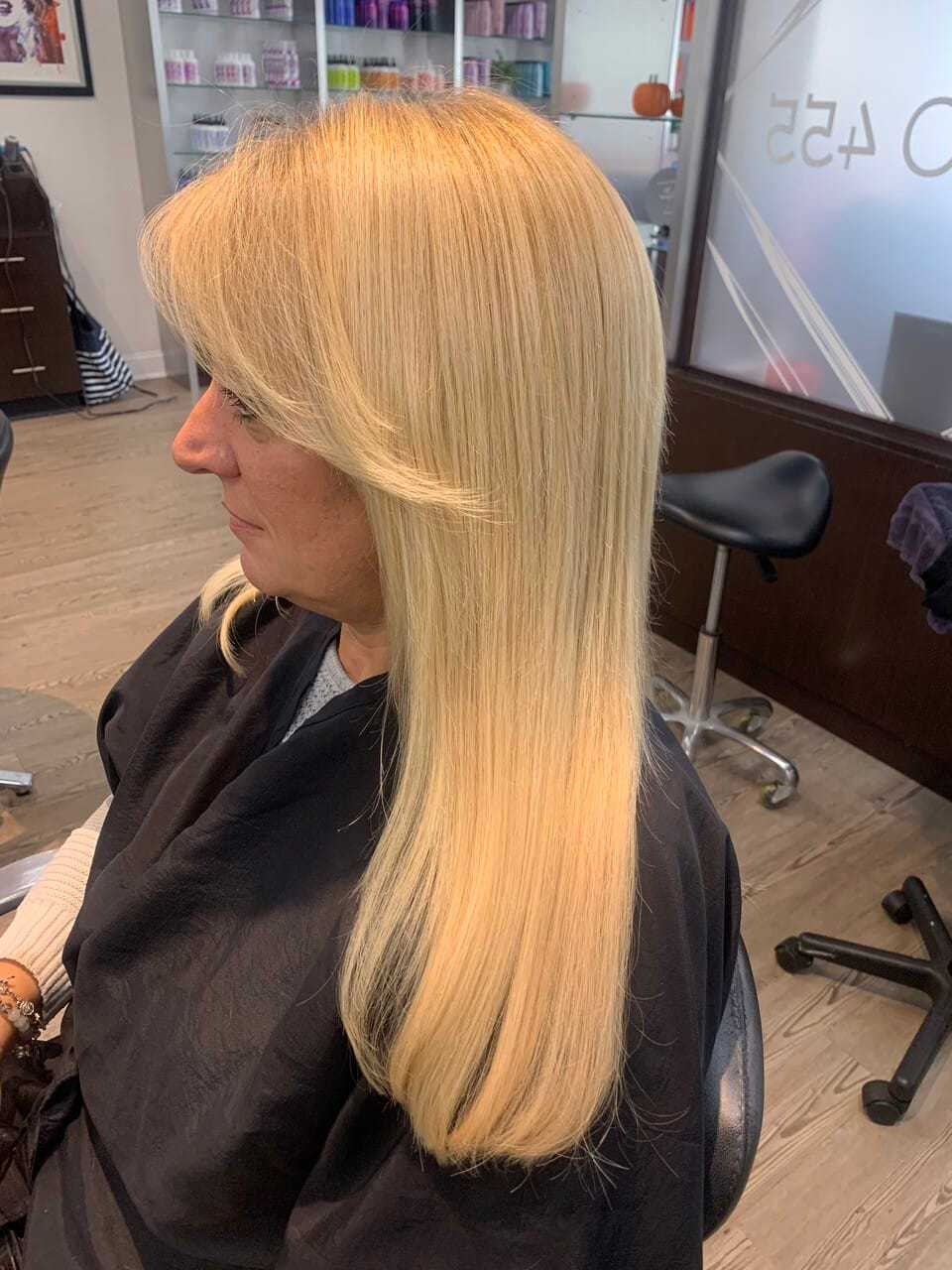 Blonde woman with long layers getting her hair styled in a salon.